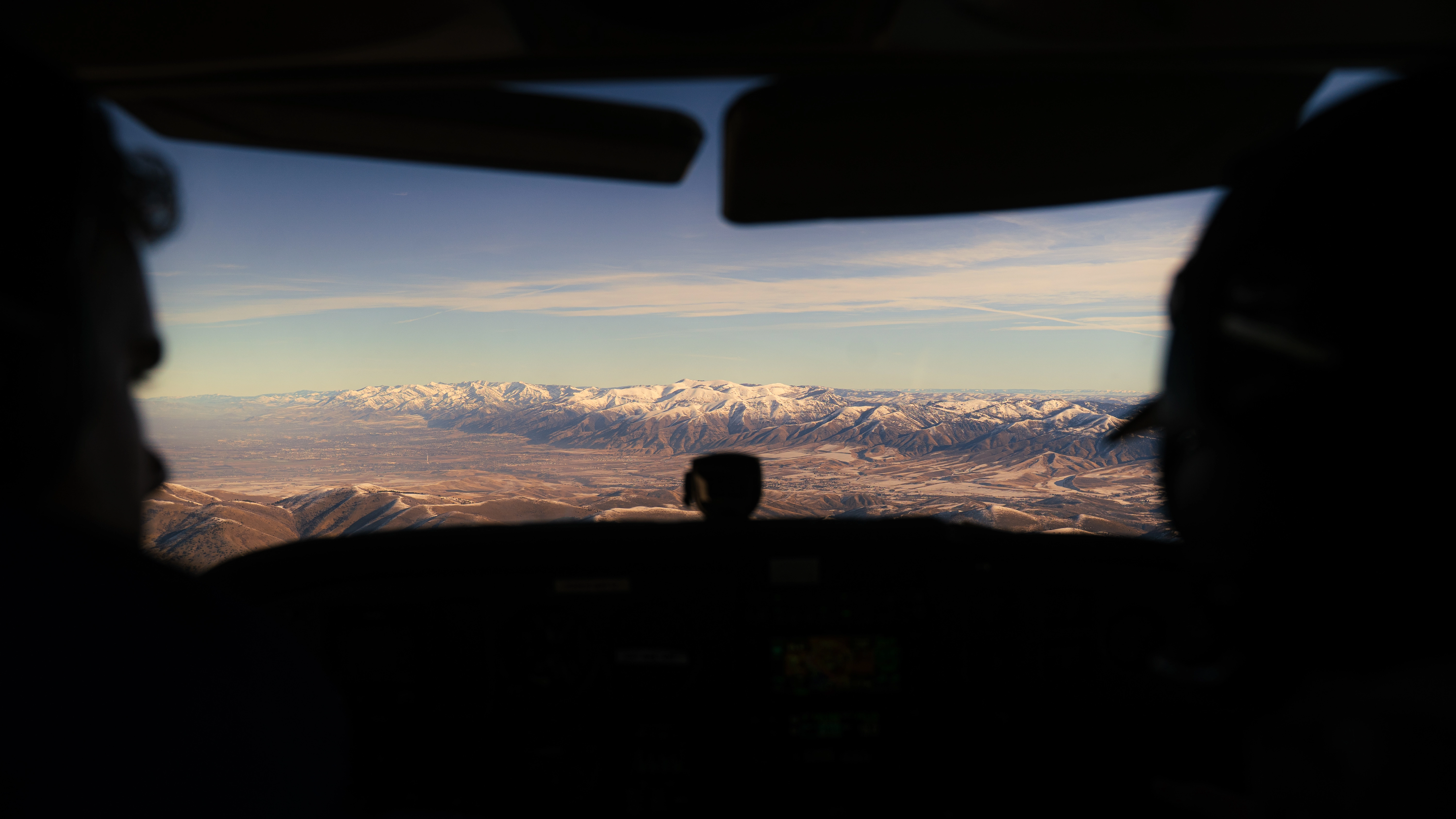 View of the back of two pilots in the cockpit while flying a plane