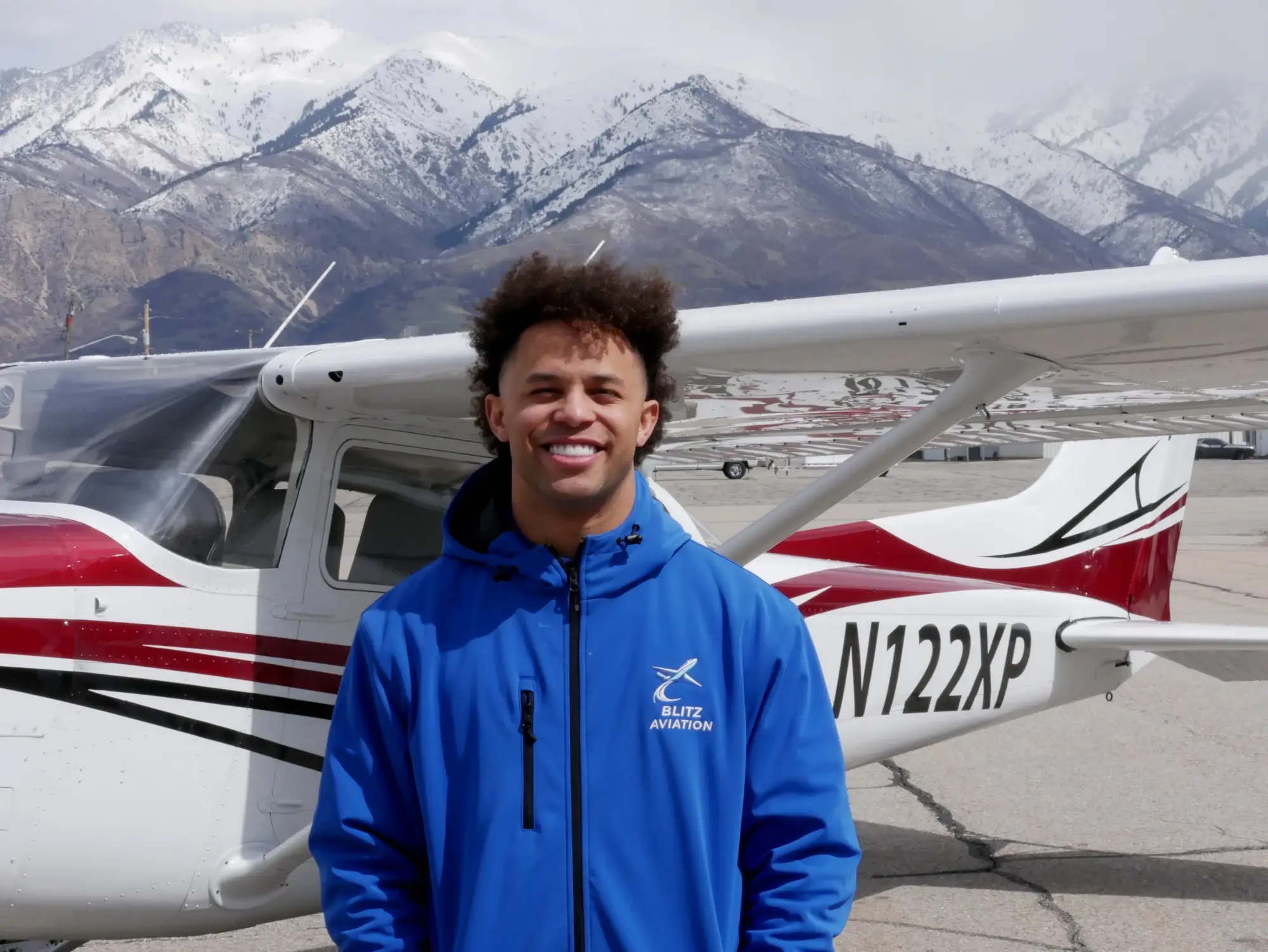Man smiling at the camera while standing in front of an airplane