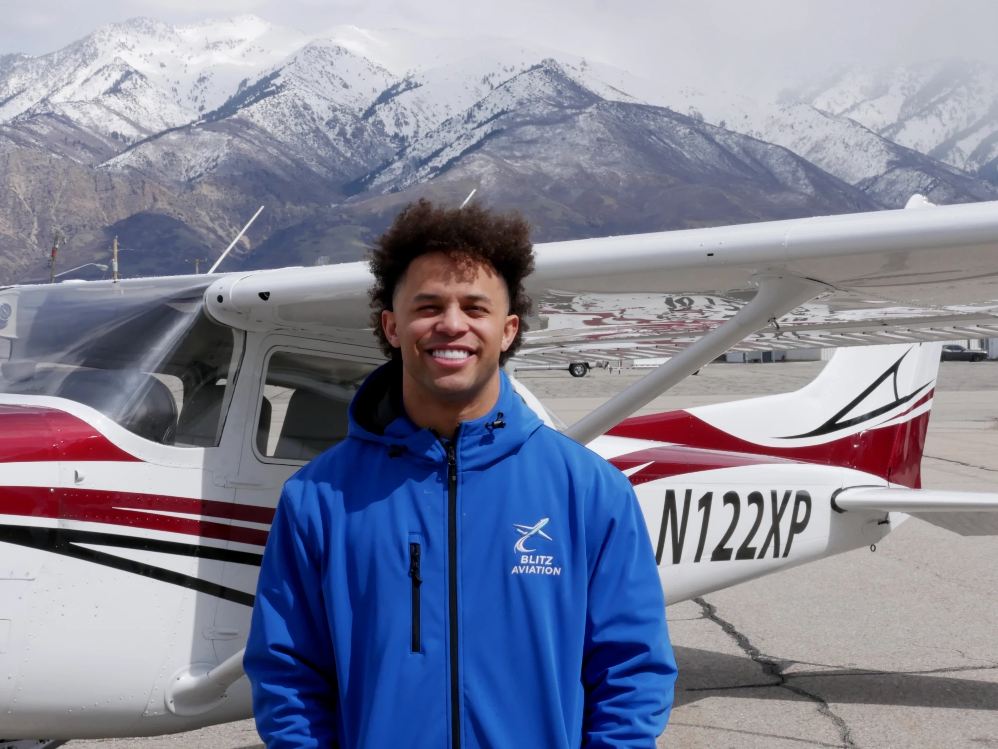 Man smiling at the camera while standing in front of an airplane