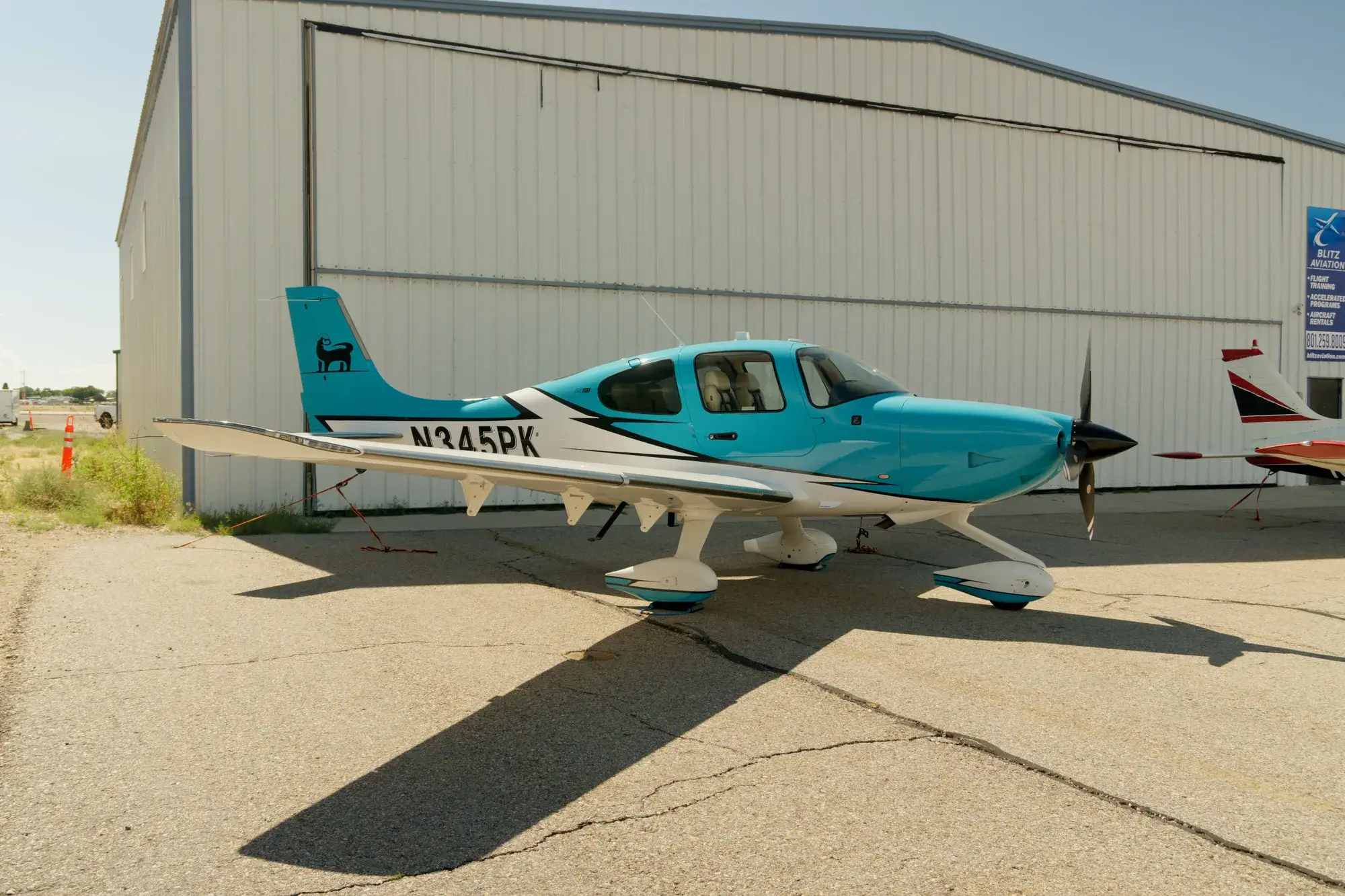 Cirrus SR22T parked beside a hangar with the Blitz Aviation sign at Ogden-Hinckley Airport