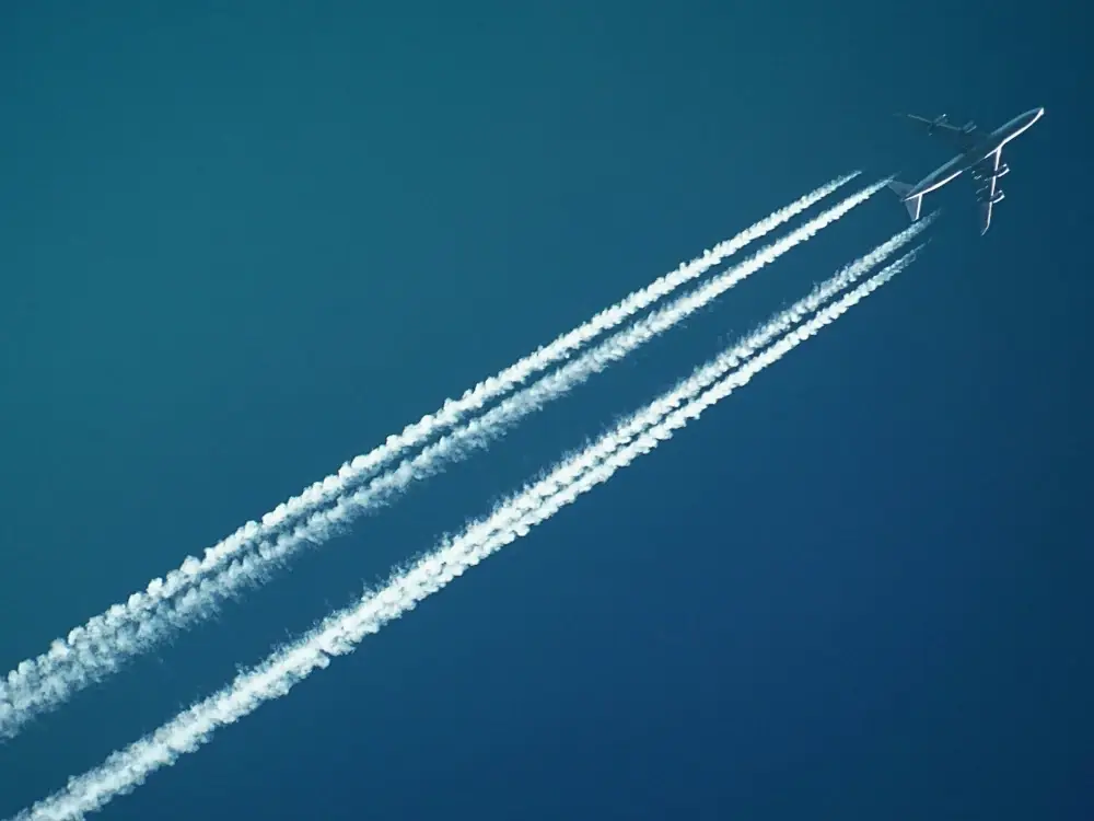 White vapor trail coming out of an airplane during flight