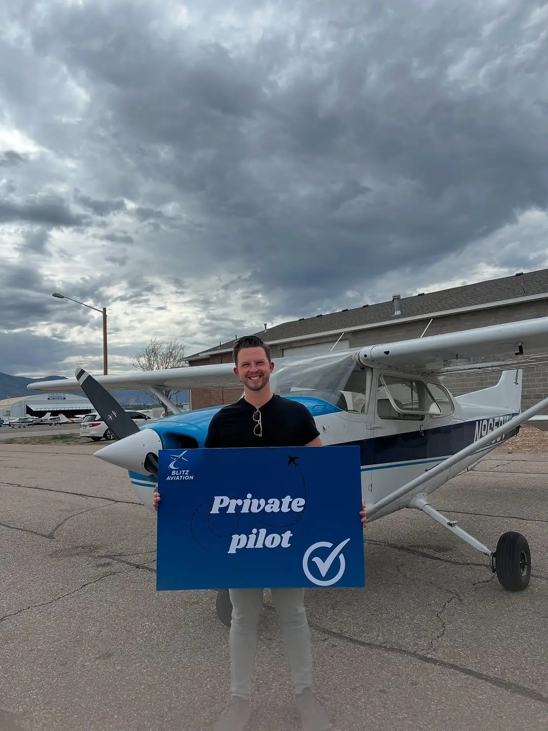 Man in front of an airplane holding a poster with "Private Pilot" written on it