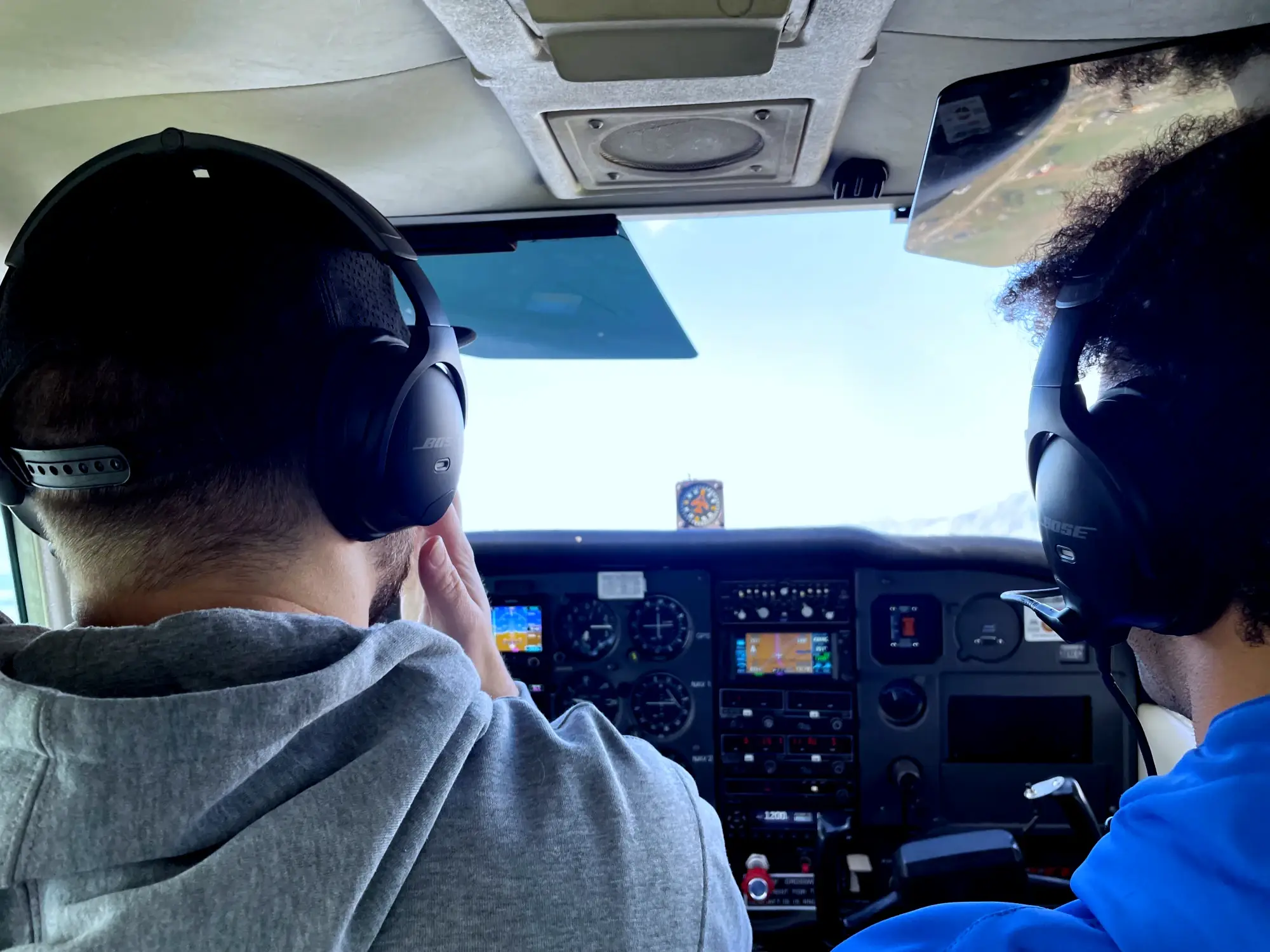 View of the back of two pilots in the cockpit while flying a plane